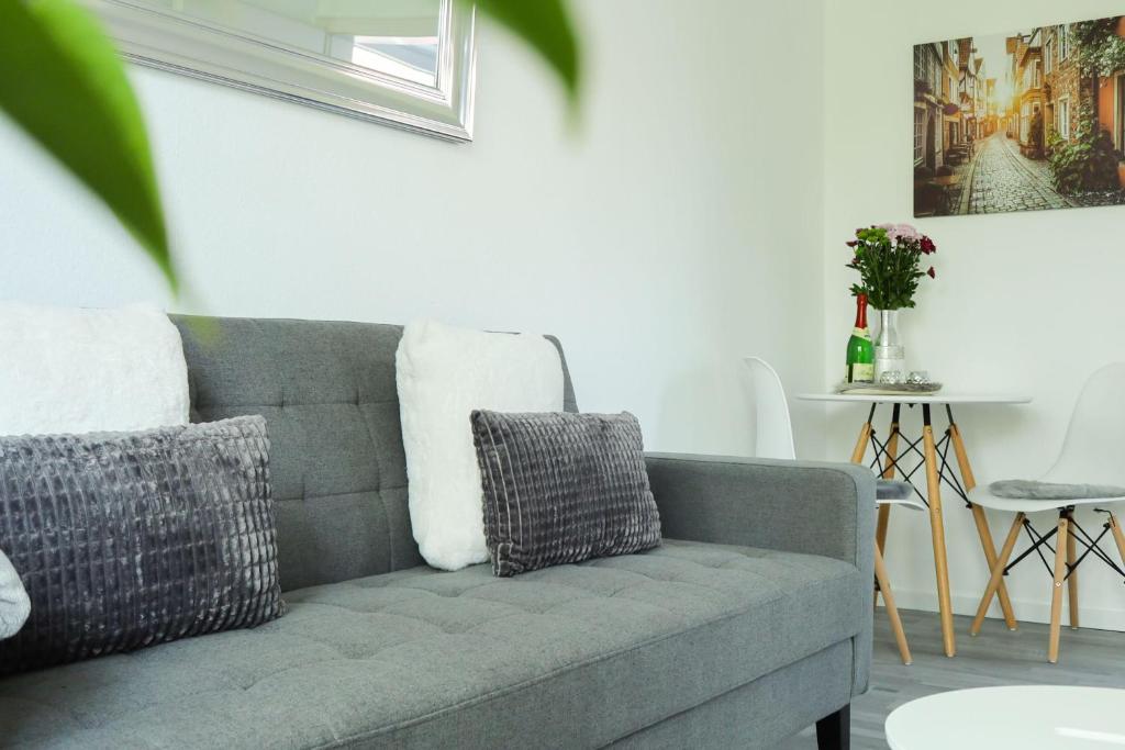 ein Wohnzimmer mit einem grauen Sofa und einem Tisch in der Unterkunft Appartement an der Ilmenau in Lüneburg