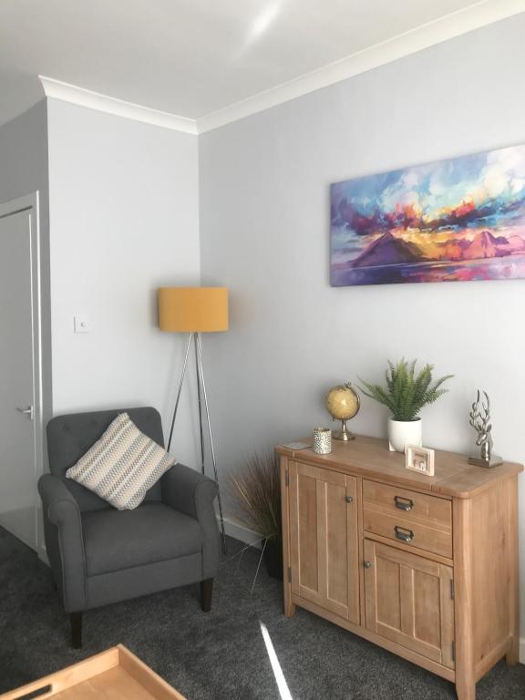 a living room with a chair and a painting on the wall at 4 York Drive, Portree , Isle Of Skye in Portree