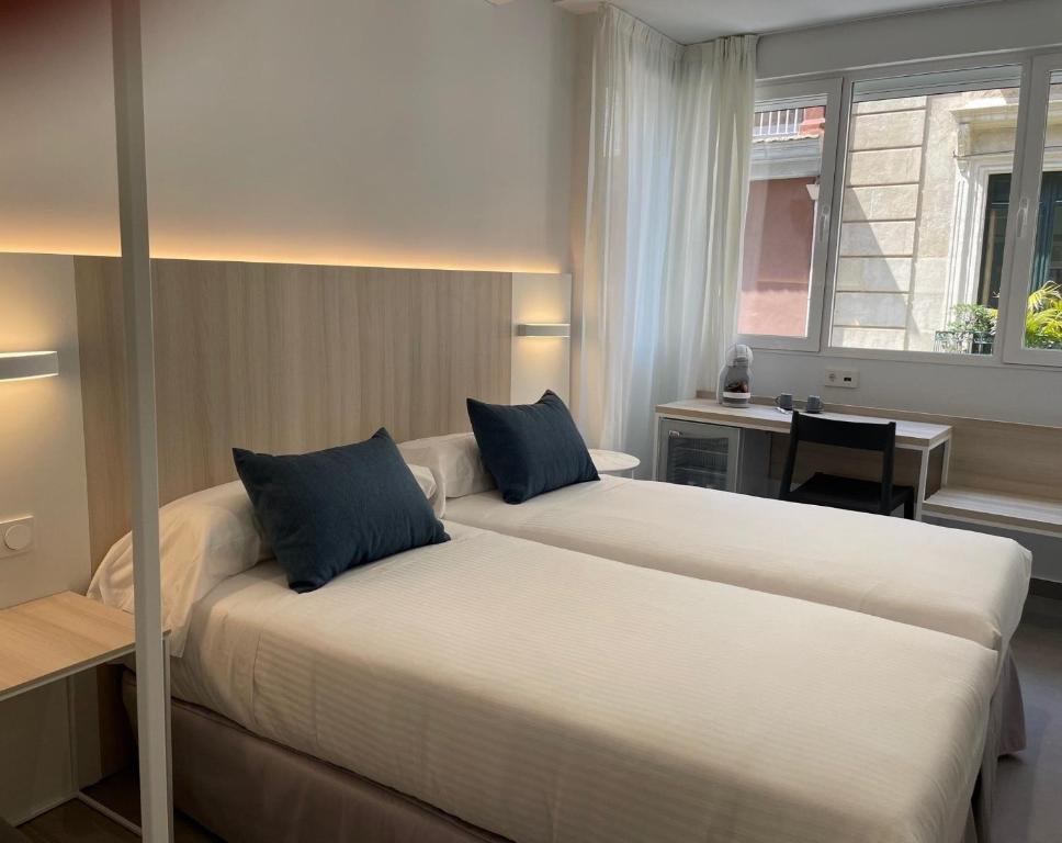 a hotel room with two beds and a desk at LC Hotel Urbano in Alicante