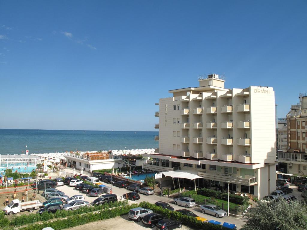a hotel with a parking lot next to the ocean at Hotel Benini in Milano Marittima