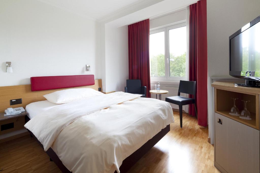 a hotel room with a large bed and a television at Swiss Star Irchel - Self Check-In in Zurich