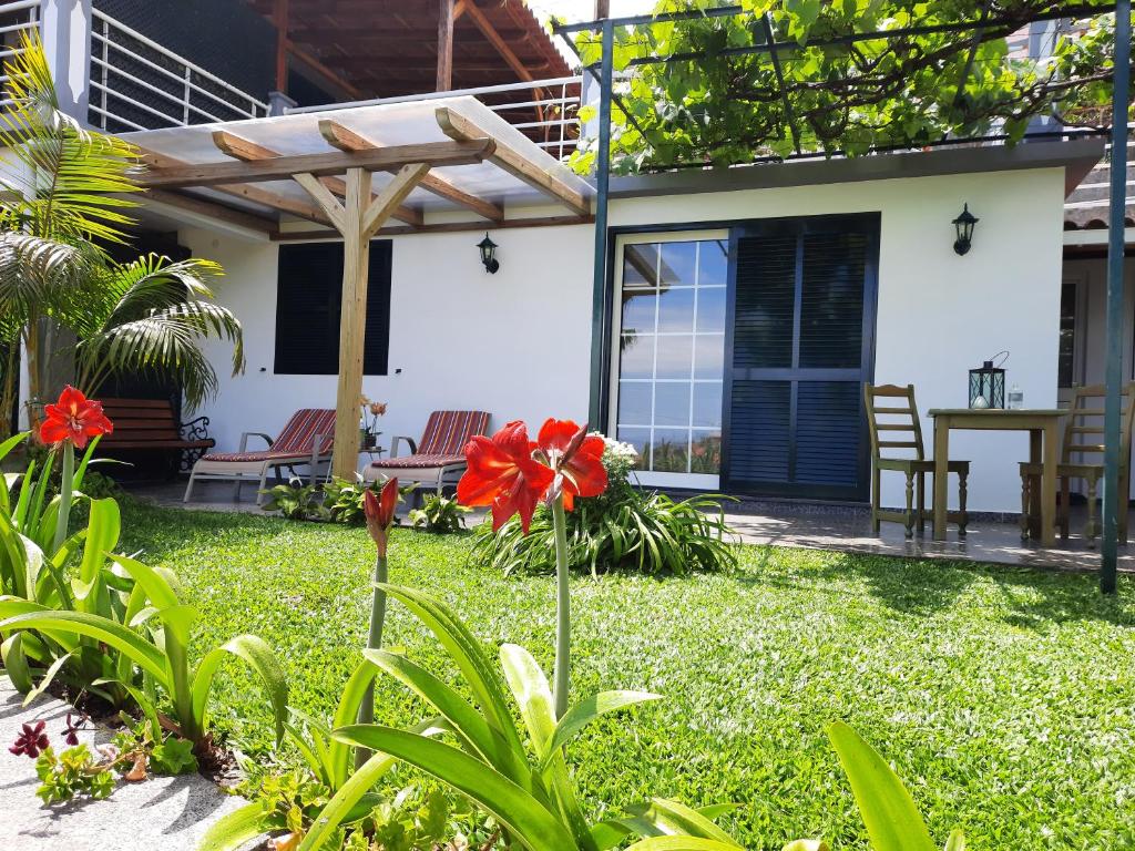 a house with a garden with a red flower in the yard at Encanto do Sol in Ponta do Sol