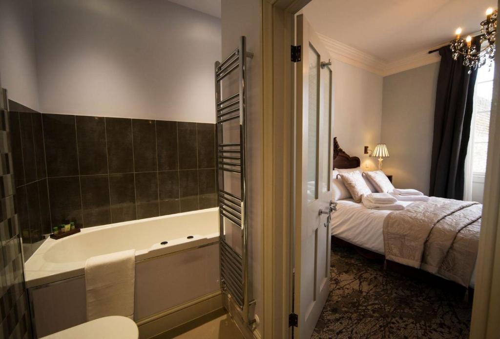 a bathroom with a bed and a bath tub next to a bedroom at East Walls Hotel in Chichester