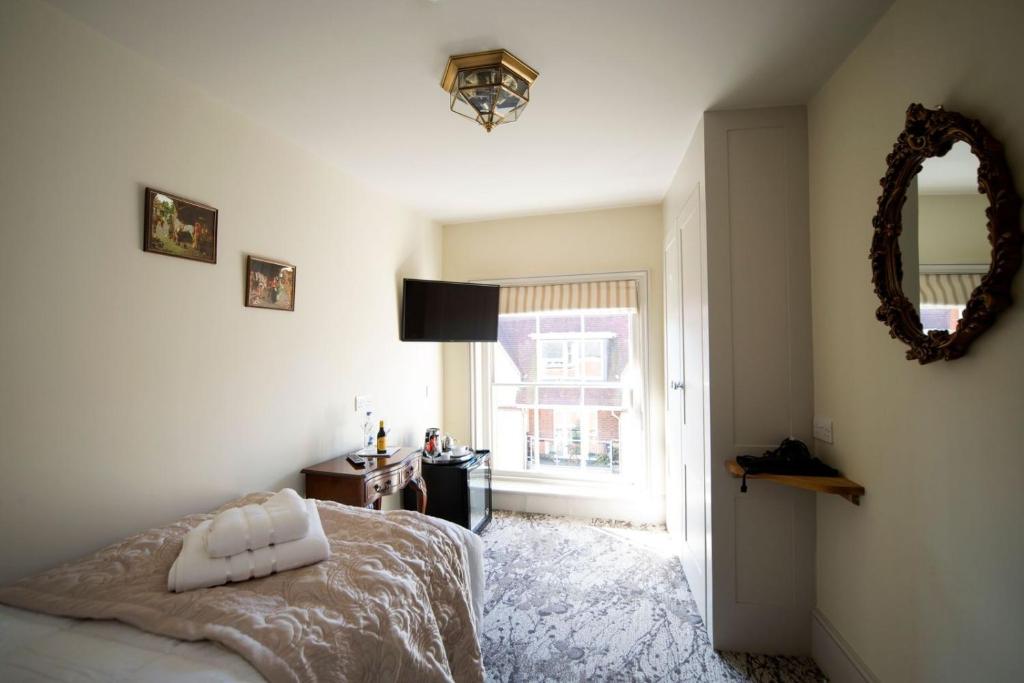 a bedroom with a bed and a mirror and a window at East Walls Hotel in Chichester