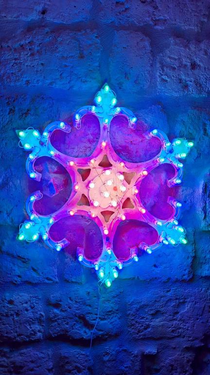 un flocon de neige violet éclairé avec des lumières sur un mur de briques dans l'établissement Loft Albicocca, à Bari