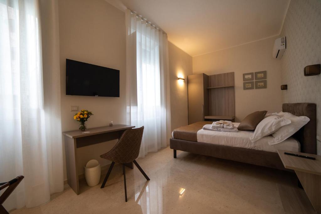 a bedroom with a bed and a desk and a television at Bebio Rooms in Trani