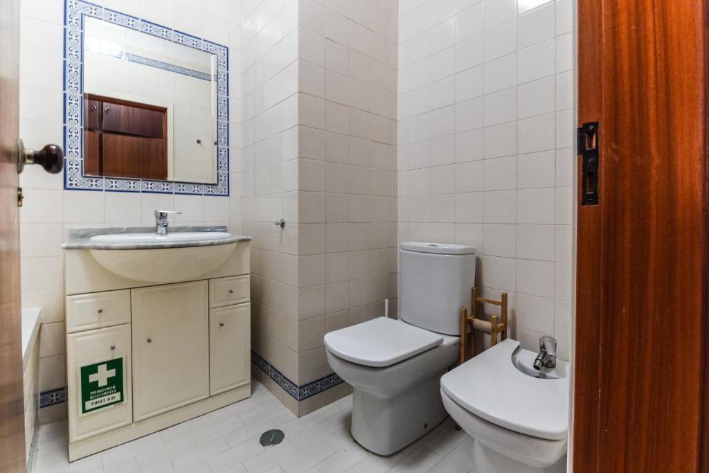 a bathroom with a toilet and a sink and a mirror at Ericeira Panoramic Sea View Apartments in Ericeira