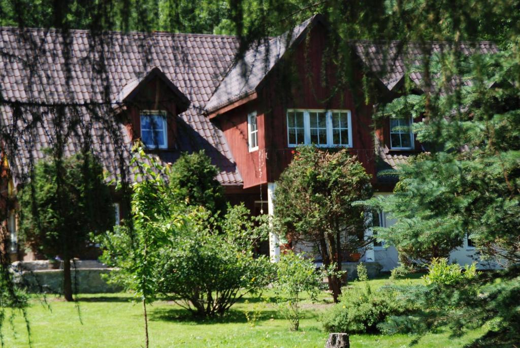 uma casa com um telhado vermelho e algumas árvores em U Robsona em Szklarska Poręba