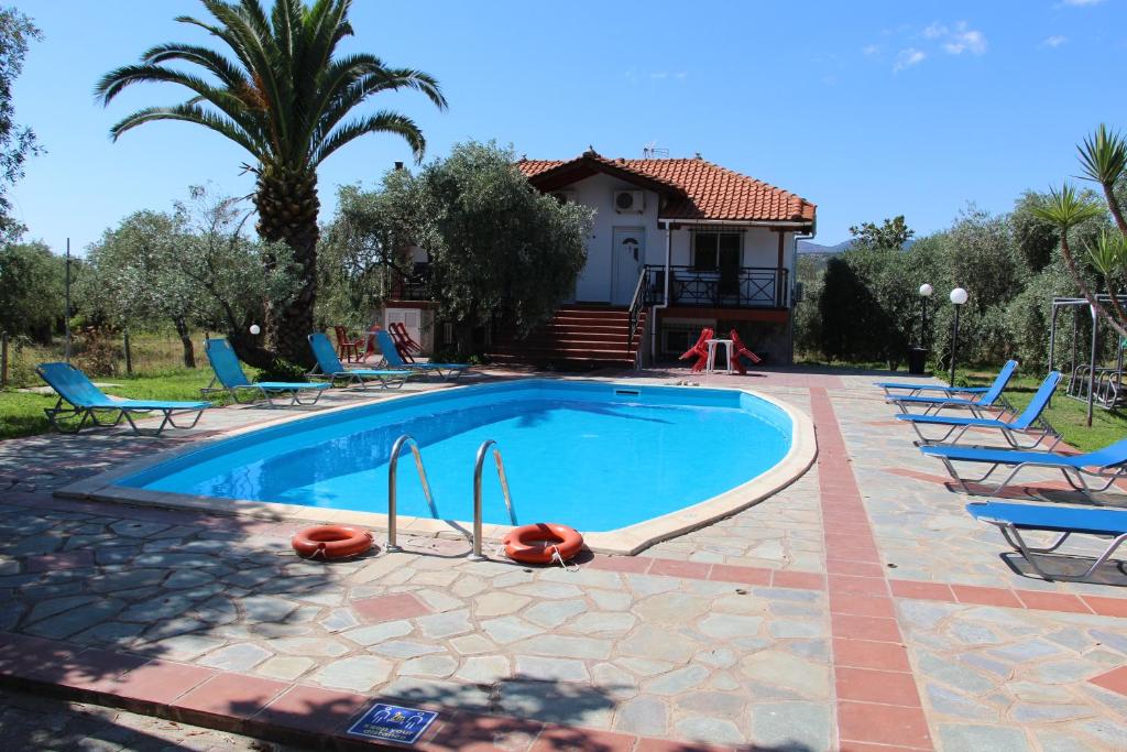 a swimming pool with chairs and a house in the background at VILLA IATROU in Potos