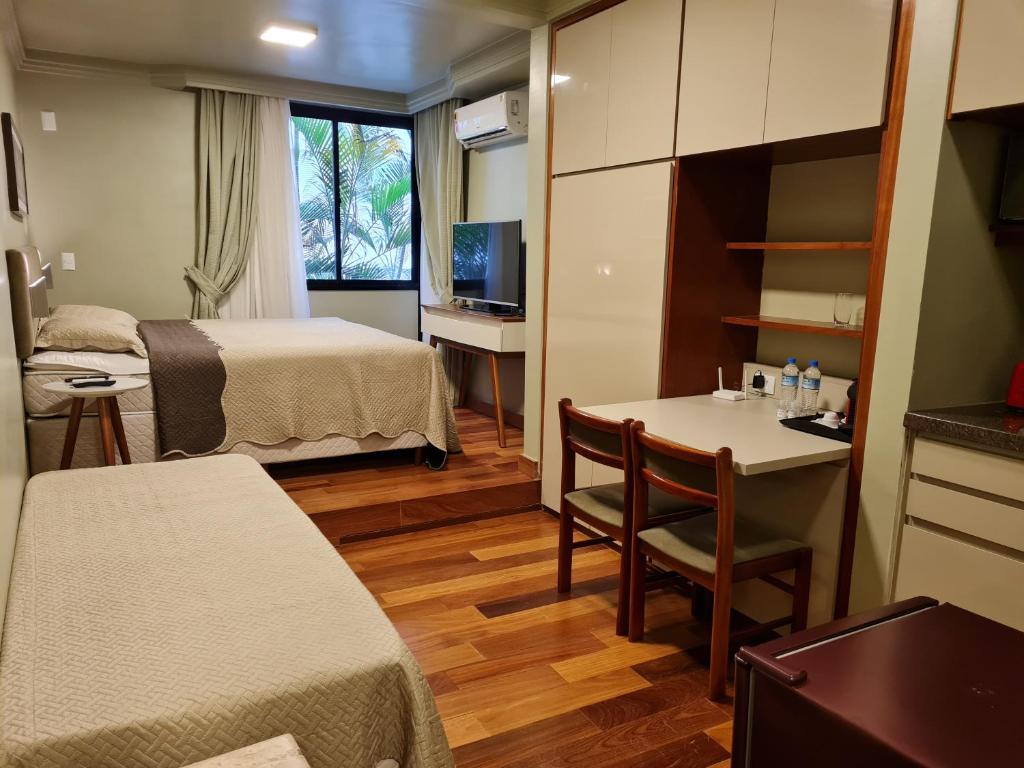 Habitación de hotel con cama y mesa con sillas en (109)Flat Poeta Drummond Jardins (Apt Particular), en São Paulo