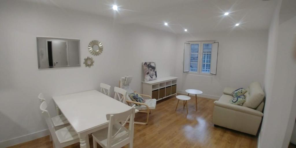 biały salon ze stołem i krzesłami w obiekcie Cómodo apartamento en zona antigua dos w mieście Pontevedra