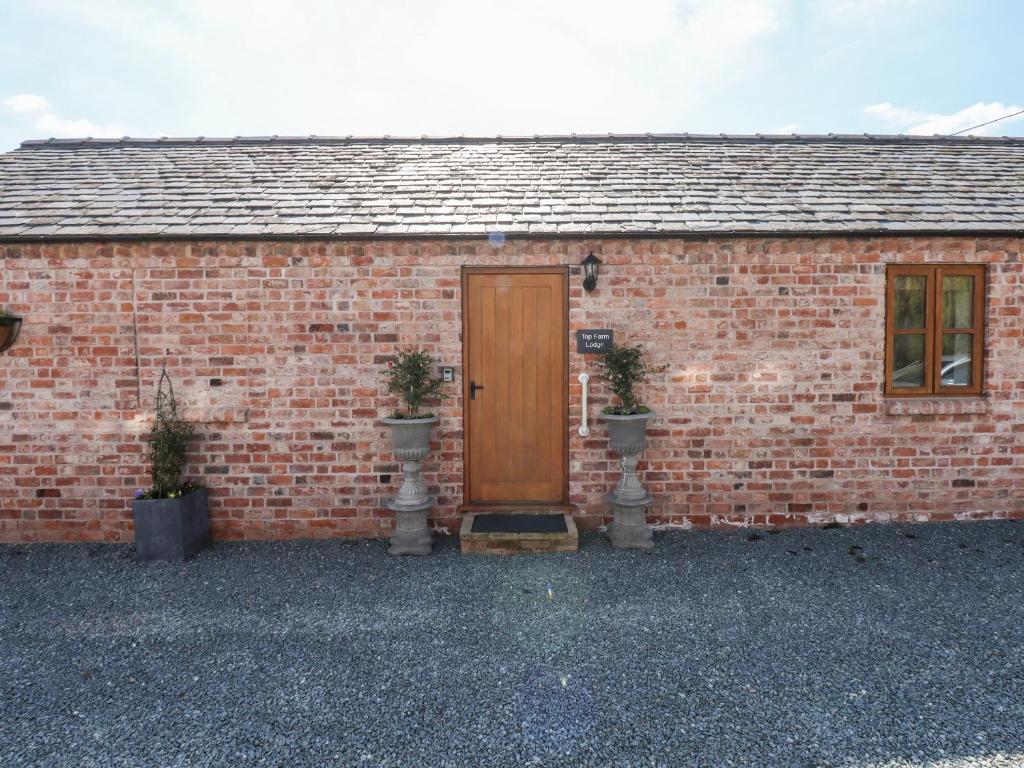 a brick building with a wooden door and two plants at Top Farm Lodge in Oswestry