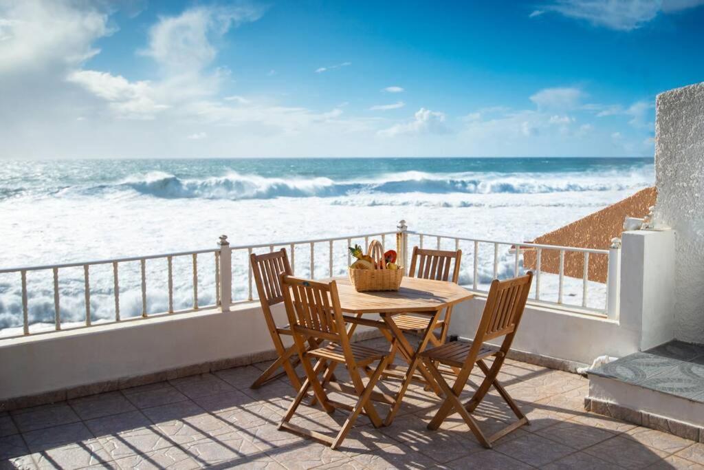 een tafel en stoelen op een balkon met uitzicht op de oceaan bij Casa do Cais in Calheta