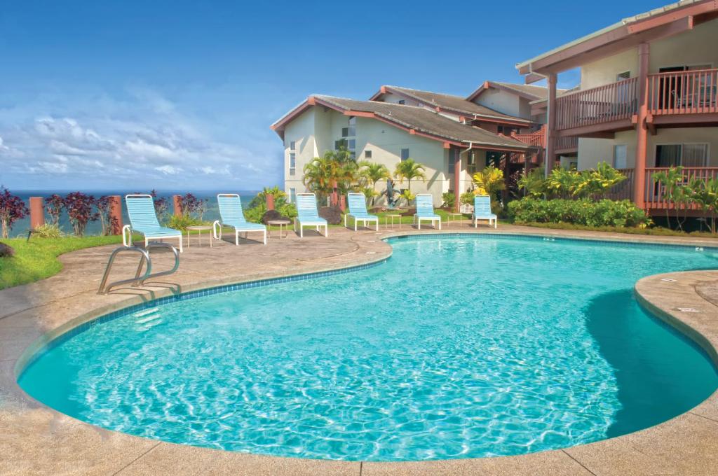 a swimming pool with chairs and a house at Club Wyndham Shearwater in Princeville