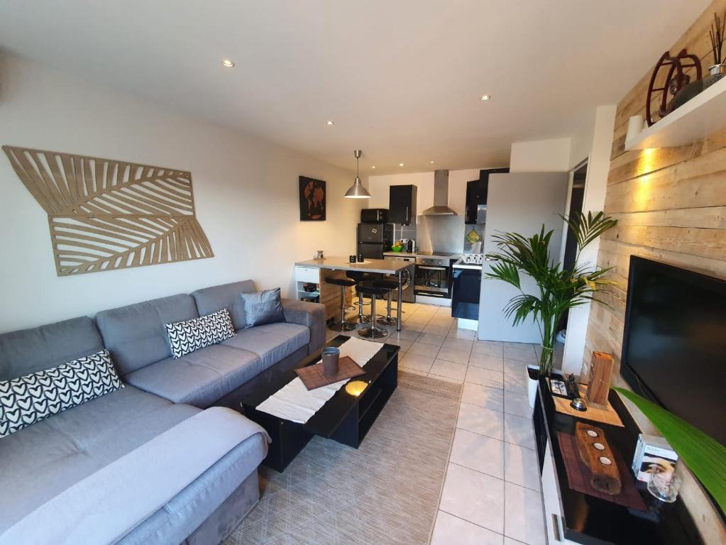 uma sala de estar com um sofá e uma mesa em Appartement 2 pièces Cosy 20 min à pied de la plage em Fréjus