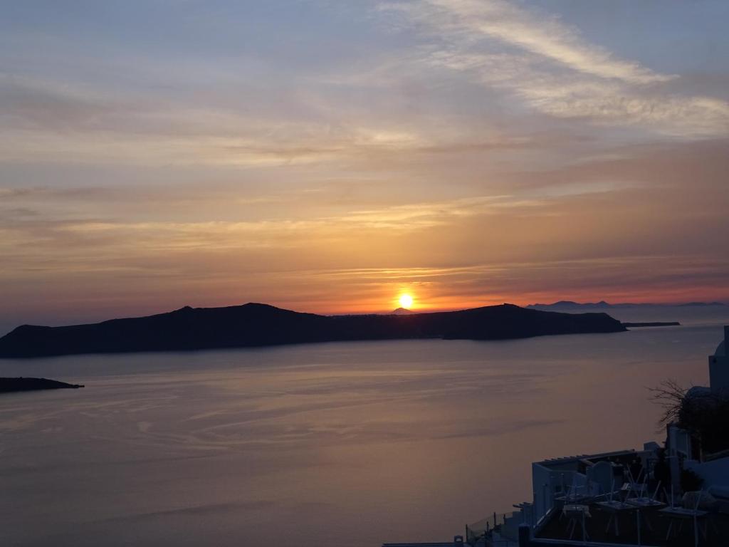 a sunset over the water with mountains in the background at NONI STUDIOS in Fira