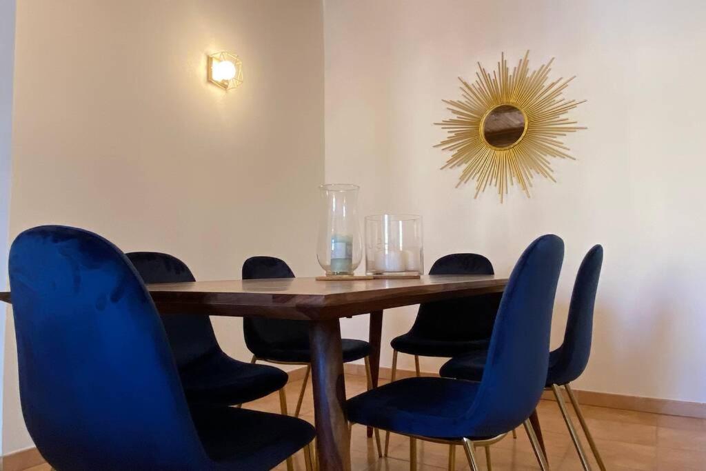 een eettafel met blauwe stoelen en een spiegel bij Très beau appartement au centre historique de Riez in Riez