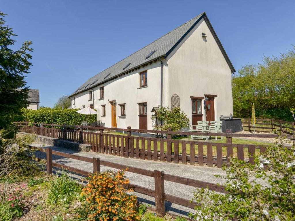 uma casa branca com uma cerca de madeira em frente em Post House em Holsworthy