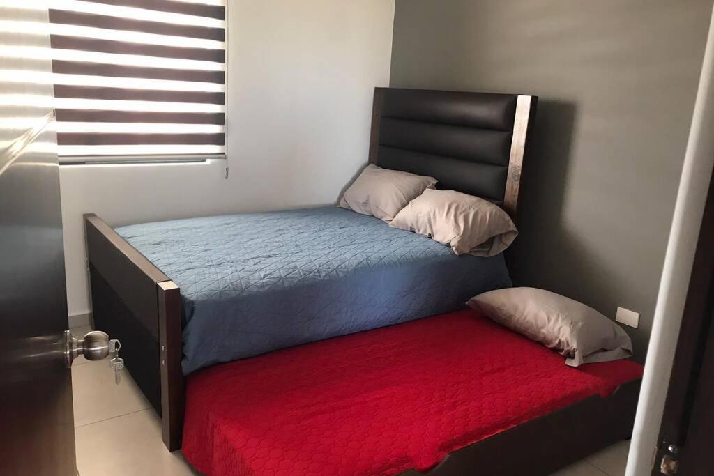 a bedroom with a bed with a red blanket at Palmilla residencial departamento en zona privada in Mazatlán