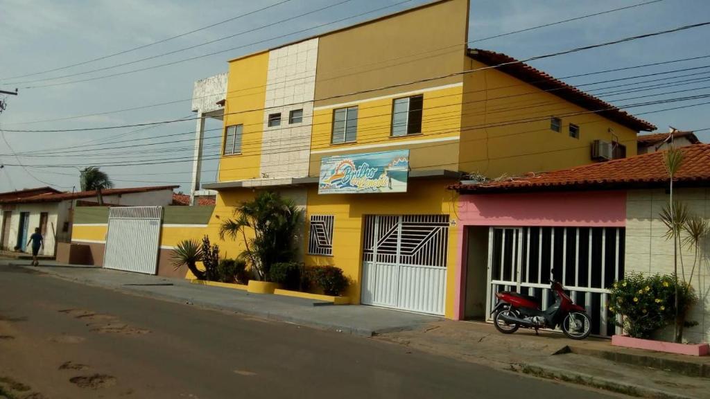 a yellow building with a scooter parked next to a street at Pousada Brilho dos Lençóis in Barreirinhas