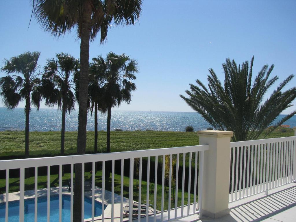 een balkon met uitzicht op de oceaan en palmbomen bij Secret Garden Residence in Paphos City