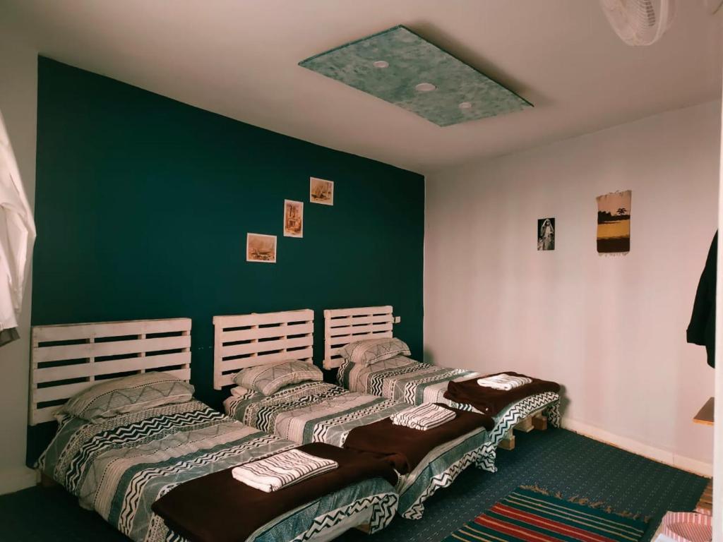 2 Betten in einem Zimmer mit grüner Wand in der Unterkunft Petra Main Gate in Wadi Musa