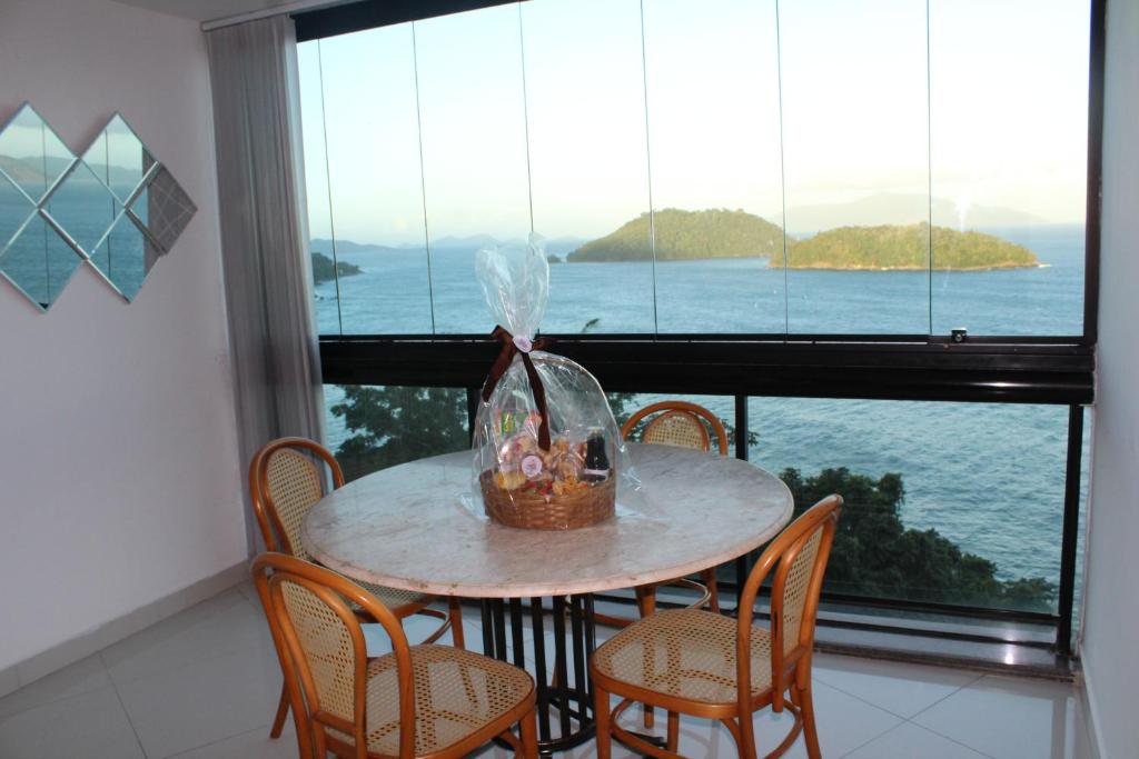 einen Tisch mit Stühlen und einen Korb mit Fenster in der Unterkunft Porto Real Resort - Apto 3 Suites Vista para o Mar in Mangaratiba
