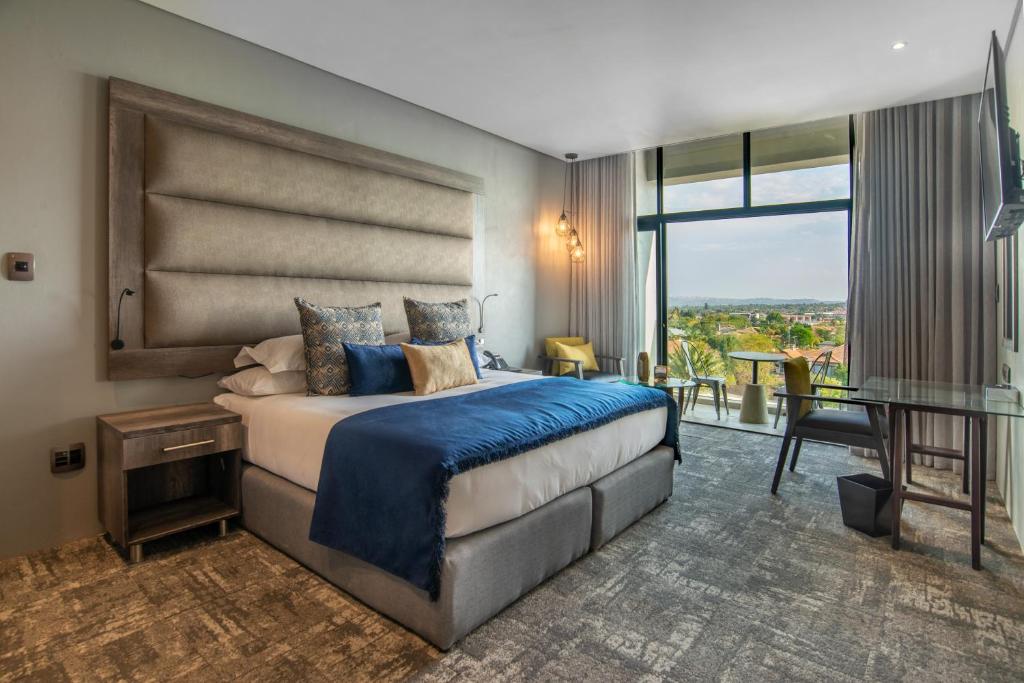 - une chambre avec un lit, une table et un balcon dans l'établissement Blueberry Hill Hotel, à Roodepoort