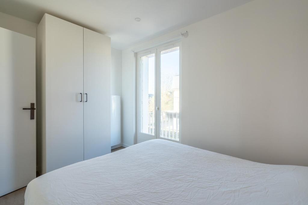 a white bedroom with a large bed and a window at Welcome perche ! Appartements 3 étoiles à NOGENT le Rotrou in Nogent-le-Rotrou