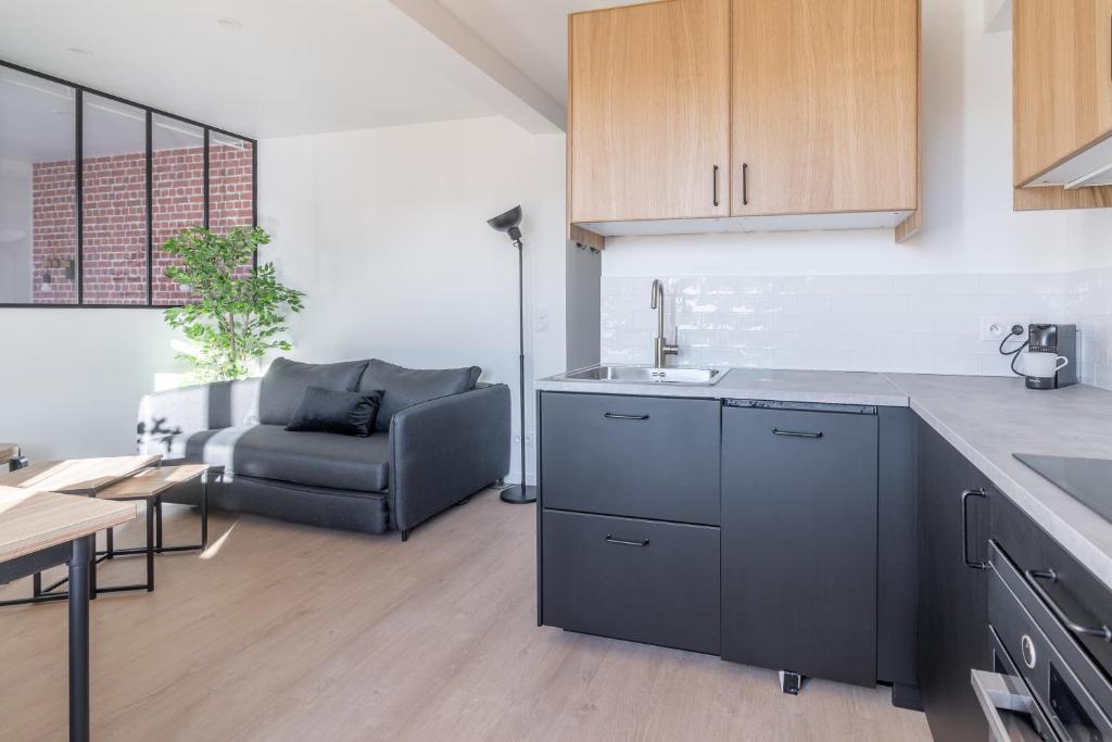 a kitchen with a sink and a couch in a room at Welcome perche ! Appartements 3 étoiles à NOGENT le Rotrou in Nogent-le-Rotrou