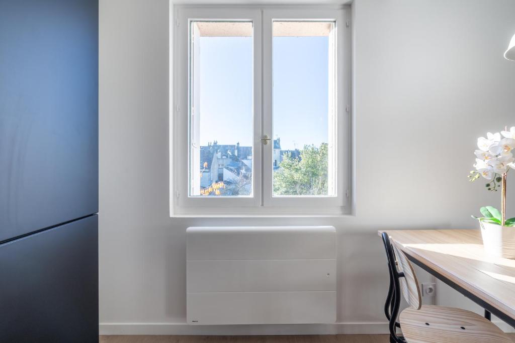 a white kitchen with a window and a desk at Welcome perche ! Appartements 3 étoiles à NOGENT le Rotrou in Nogent-le-Rotrou