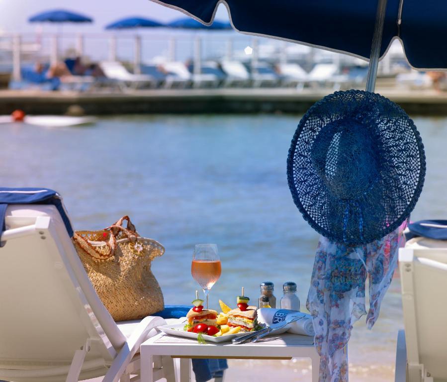 a table with a hat and a glass of wine at Hôtel Belles Rives in Juan-les-Pins