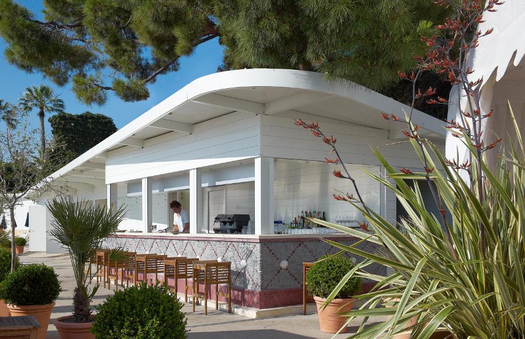 a white building with chairs in front of it at Hôtel Belles Rives in Juan-les-Pins