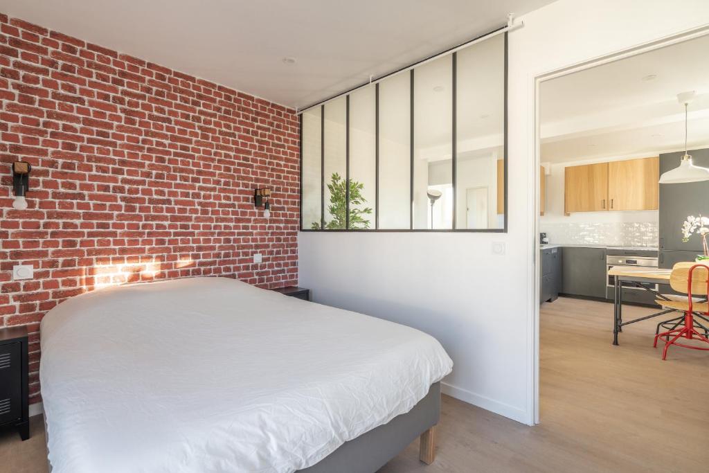 a bedroom with a brick wall and a bed at Welcome perche ! Appartements 3 étoiles à NOGENT le Rotrou in Nogent-le-Rotrou