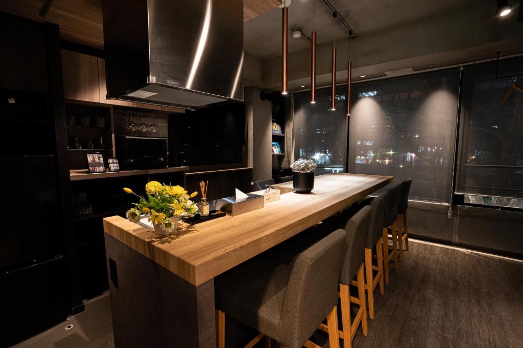 a kitchen with a long wooden counter with chairs at trive sakae 最大7名宿泊可能 矢場町駅徒歩3分 栄 大須観音スグ in Nagoya