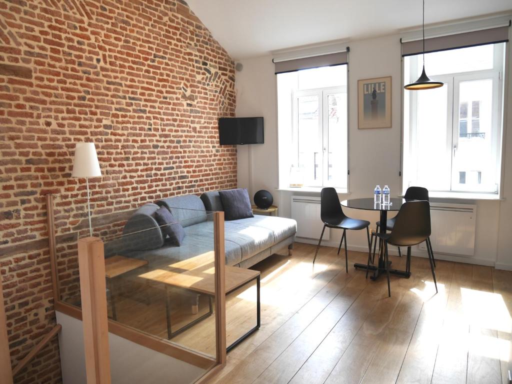 a living room with a couch and a brick wall at Le Chat Qui Dort in Lille