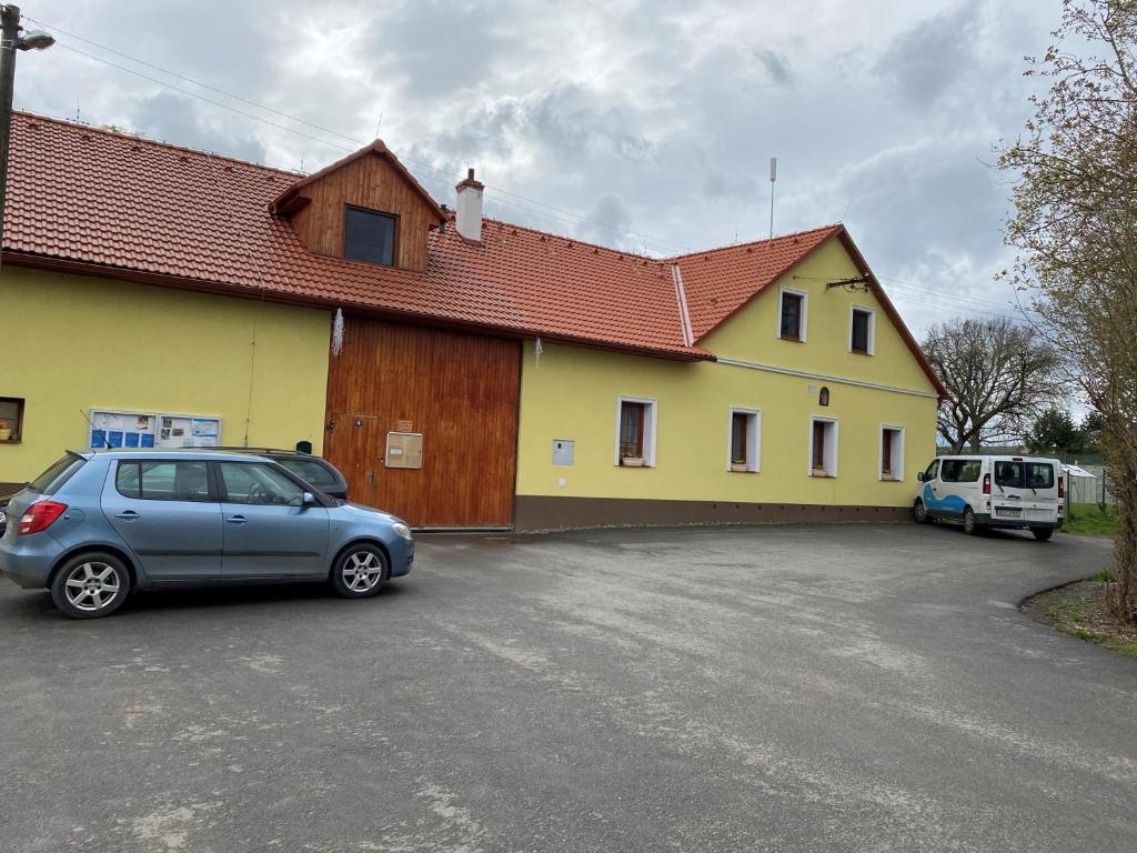 una casa amarilla con un coche aparcado en un aparcamiento en Buchtův statek en Vendolí