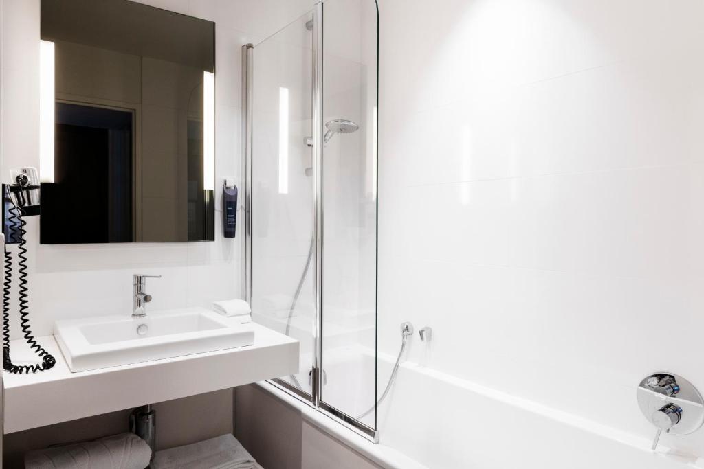 a white bathroom with a sink and a shower at Hôtel Le Windsor Biarritz in Biarritz