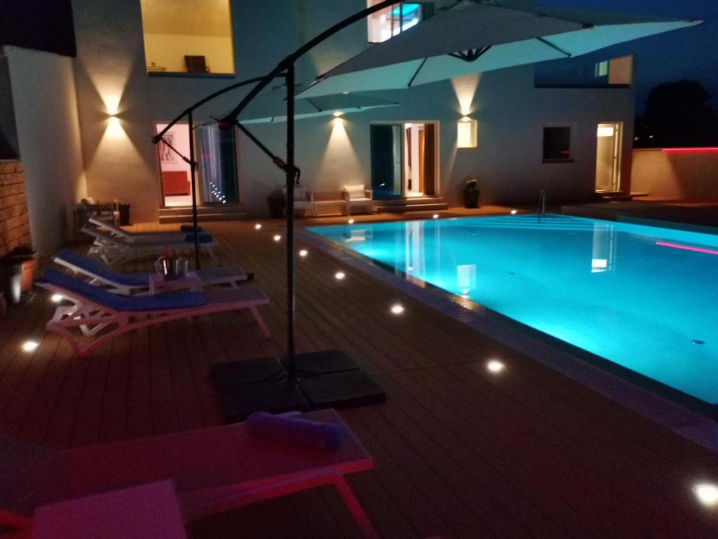 a pool with chairs and an umbrella at night at Villa Pasis in Rovinj