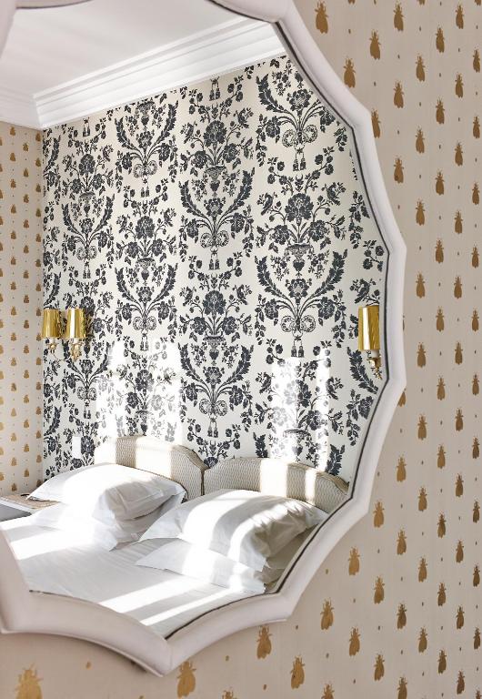a bedroom with a bed with a damask wallpaper at Hôtel Belles Rives in Juan-les-Pins