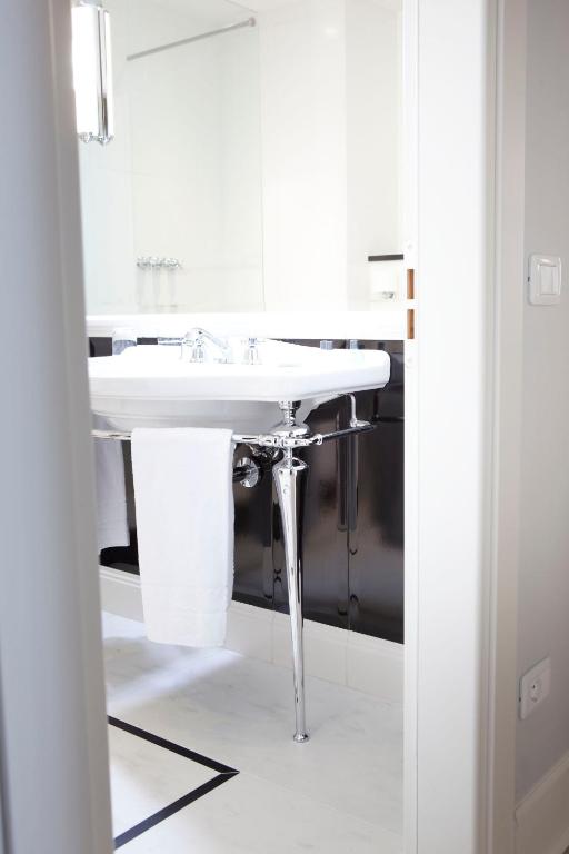 a white bathroom with a sink and a mirror at Hotel Riviera & Maximilian's in Trieste
