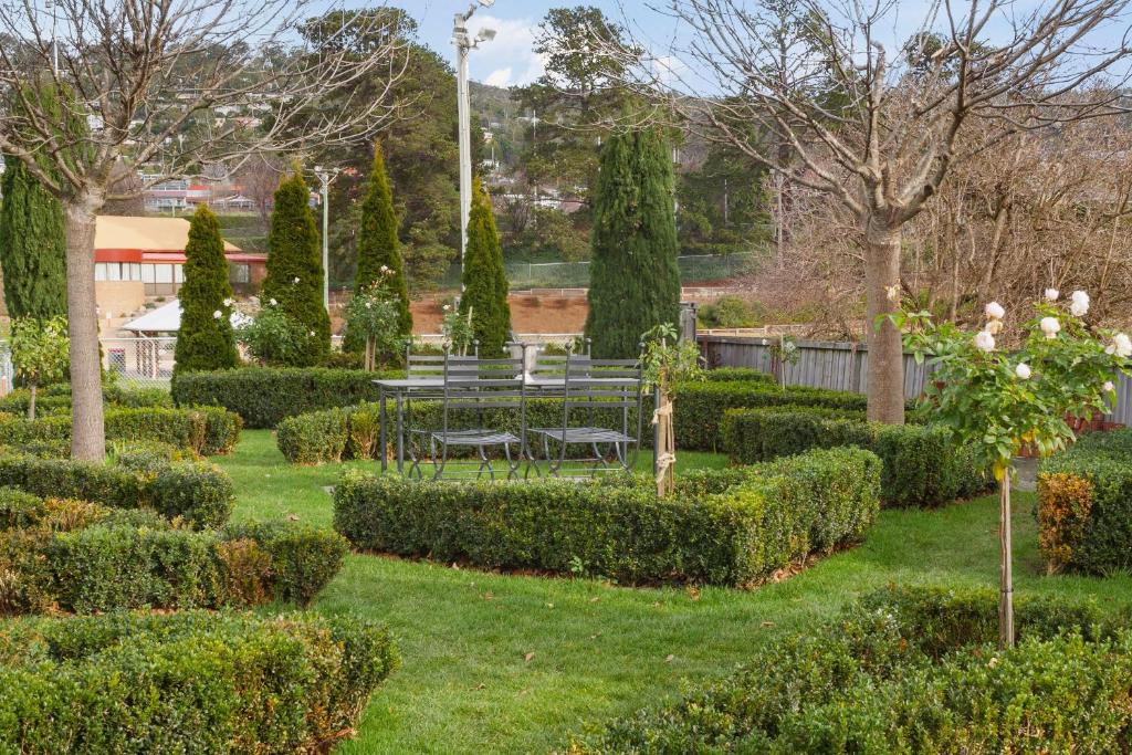 a garden with a table and chairs and bushes at The Rivulet in Hobart