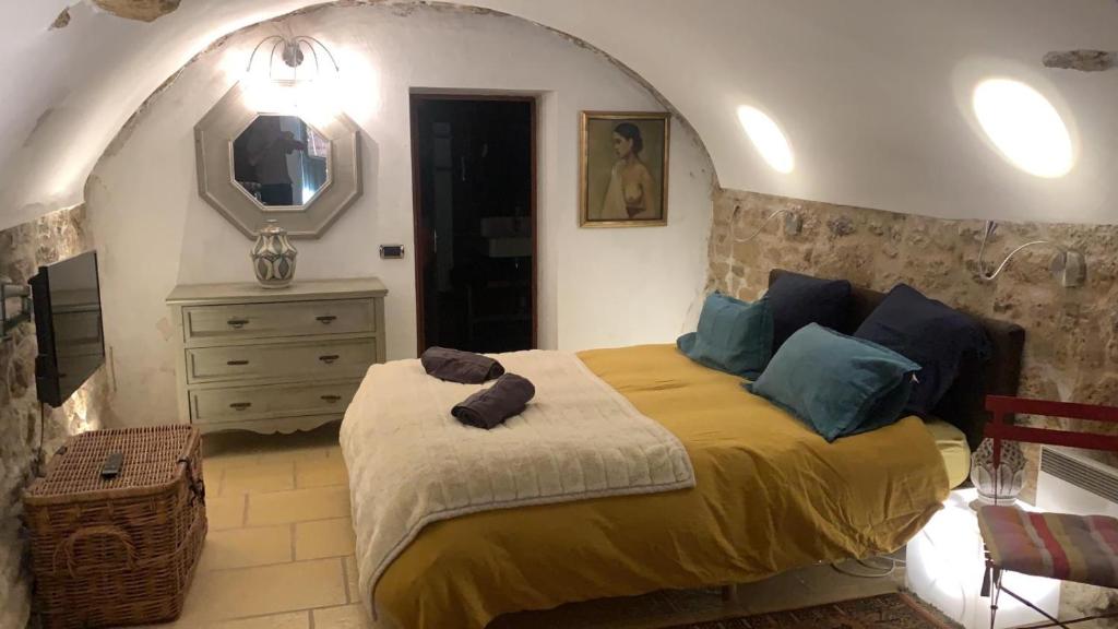 ein Schlafzimmer mit einem Bett, einem Spiegel und einer Kommode in der Unterkunft la villageoise, chambre troglodyte pitoresque au cœur du village in Rognes