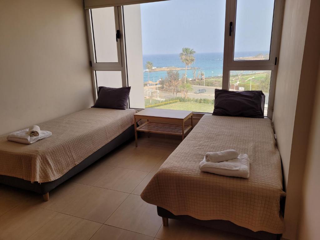 two beds in a room with a view of the ocean at PALLINIO COURT 402 Fig Tree Bay- Protaras Beach, IASONOS STR 7A in Protaras