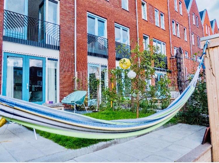 a blue hammock in front of a brick building at Canal House - Homestay in Alkmaar