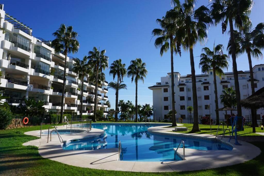 een zwembad met palmbomen voor een gebouw bij Beachside apartment Mi Capricho Portal 7 in Sitio de Calahonda