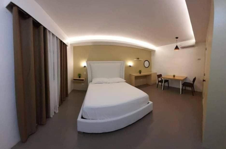ALESSANDRA HOTEL في Calaca: غرفة نوم بسرير ابيض كبير وطاولة