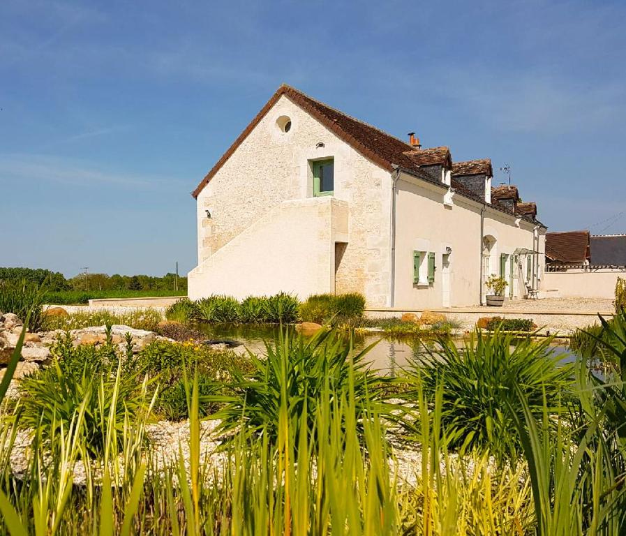 uma casa com muitas plantas à frente dela em Gîte Les Nymphéas em Épeigné-les-Bois