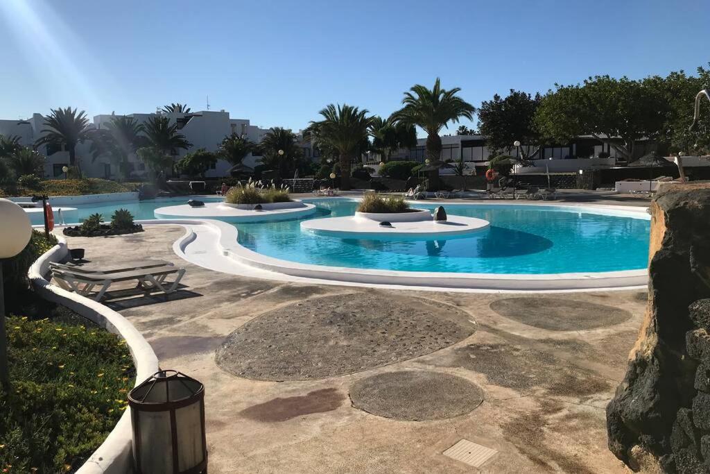 een groot zwembad met blauw water in een resort bij Home Secret relax, pool , wifi, in Costa Teguise