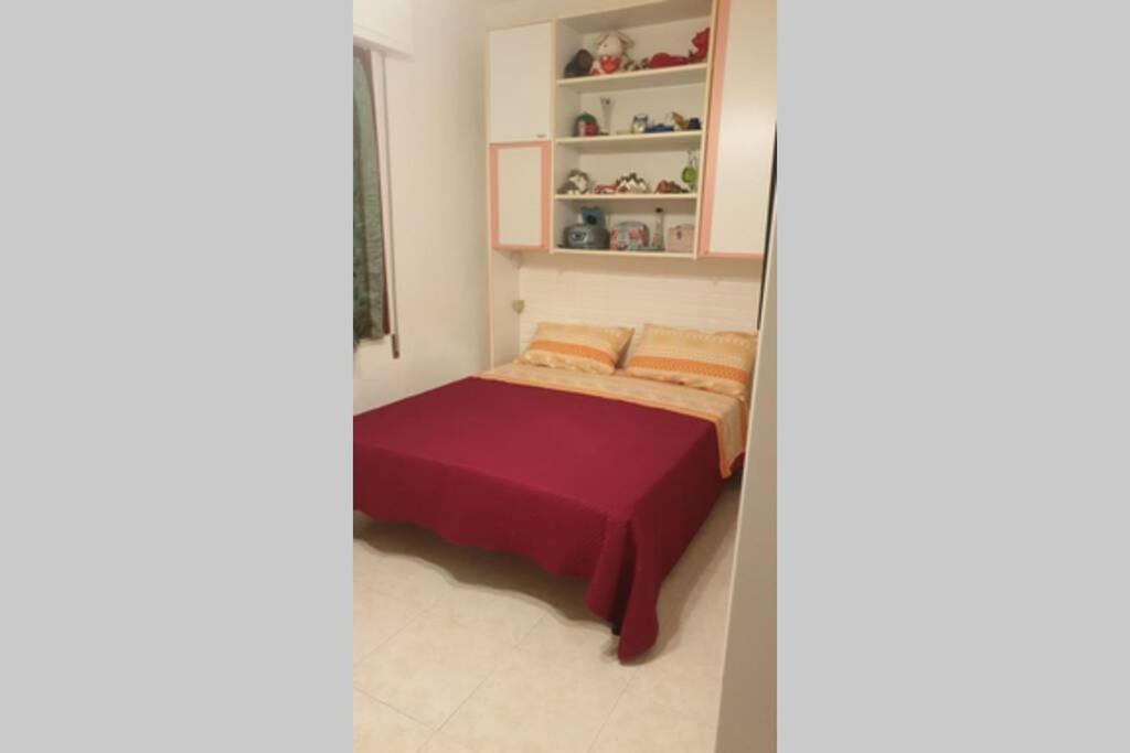 a small bedroom with a bed with a red blanket at Palma BnB in Maracalagonis